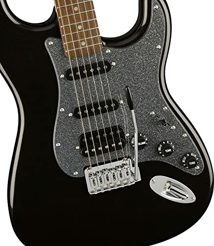 Close-up of a black electric guitar with a glittery pickguard.