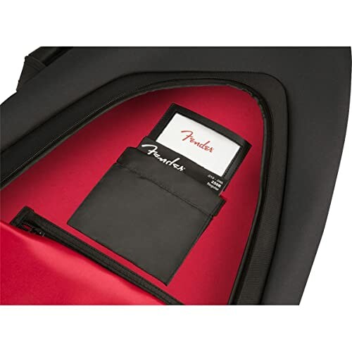 Open guitar case pocket with Fender branded accessories.