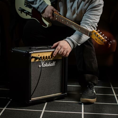 Person adjusting amplifier with guitar in hand