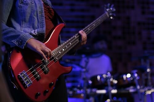 Person playing red bass guitar on stage