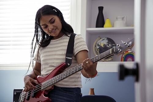 Woman playing a red bass guitar indoors.